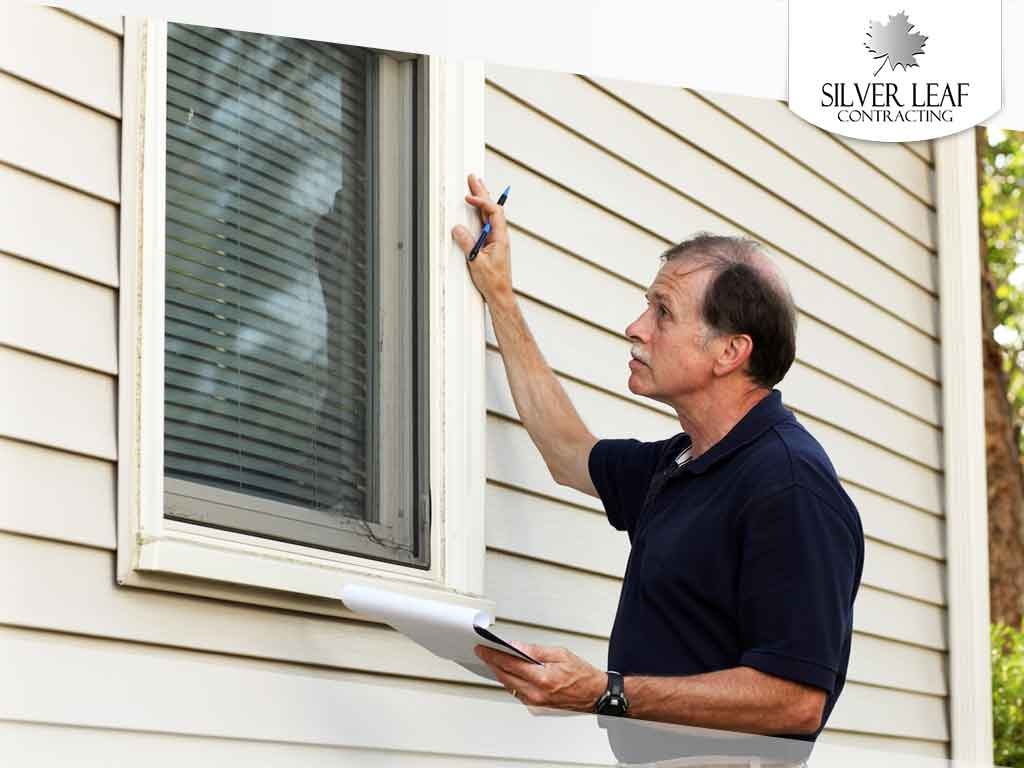 A supervisor inspects a home window.