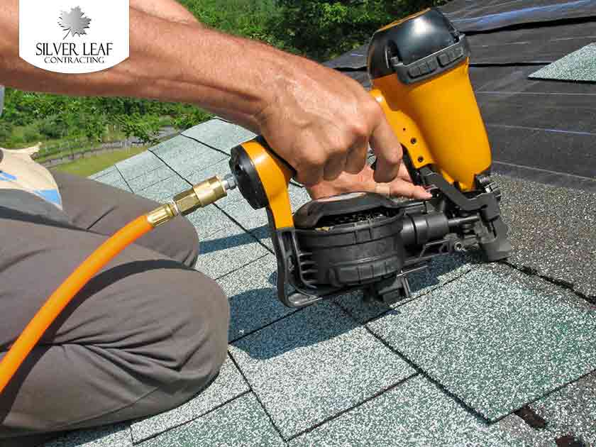A worker installs an asphalt shingle roof.